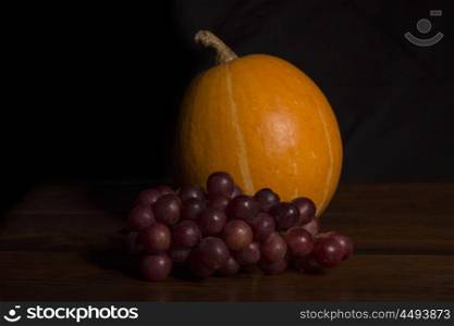 Pumkin and grapes in the dark background, studio picture