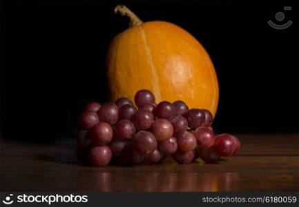Pumkin and grapes in the dark background, studio picture
