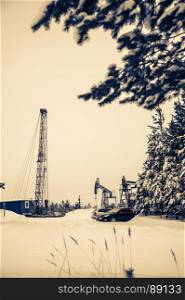 Pump jack and oil rig in the oilfield situated in the beautiful winter forest. Environmental pollution. Oil and gas concept. . Pump jack and oil rig situated in forest.