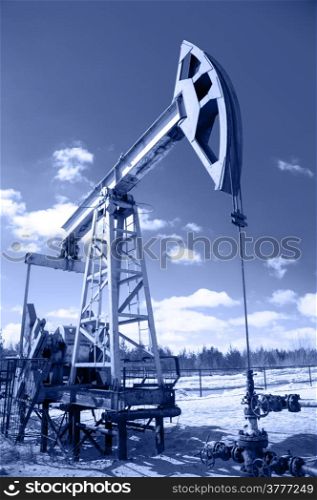 Pump jack and wellhead with valve armature. Extraction of oil. Toned.