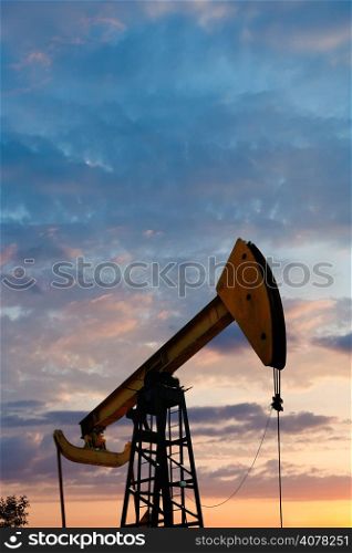 pump jack extracts oil in Caucasus region at summer sunset