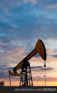 pump jack extracts oil in Caucasus region at summer sunset