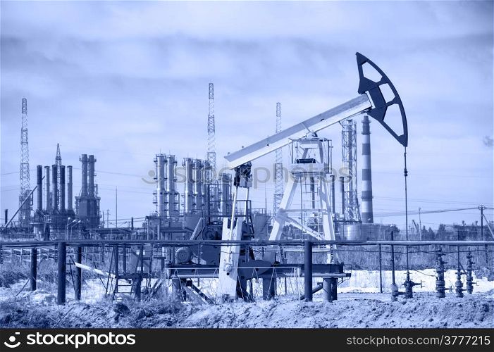Pump jack on a background of petrochemical plant. Oil and gas industry.