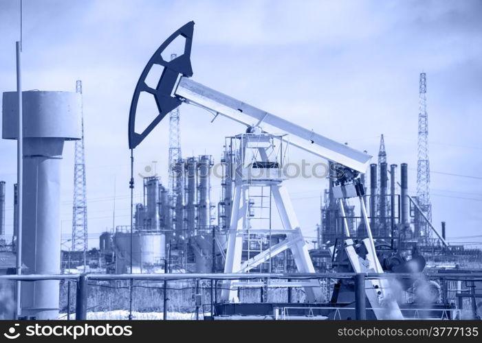 Pump jack on a background of petrochemical plant. Oil and gas industry. Toned.