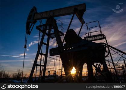 Pump jacks at sunset sky background. Extraction of oil. Petroleum concept.