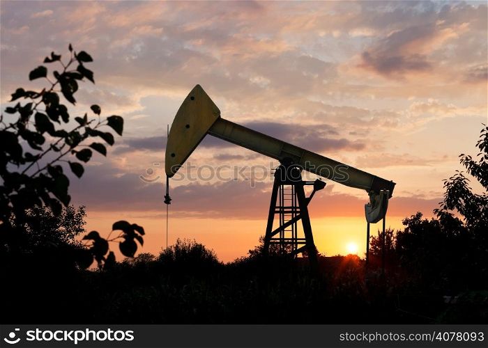 pumpjack pumps oil in Caucasus region at summer sunset