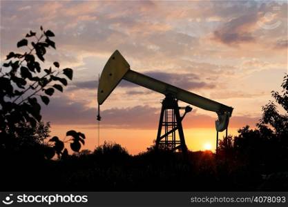 pumpjack pumps oil in Caucasus region at summer sunset