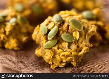 Pumpkin and oatmeal drop cookies with pumpkin seeds on top, photographed with natural light (Selective Focus, Focus in the middle of the cookie)