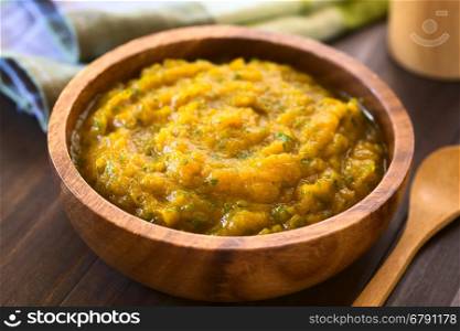 Pumpkin and parsley puree in wooden bowl, photographed with natural light (Selective Focus, Focus one third into the puree)