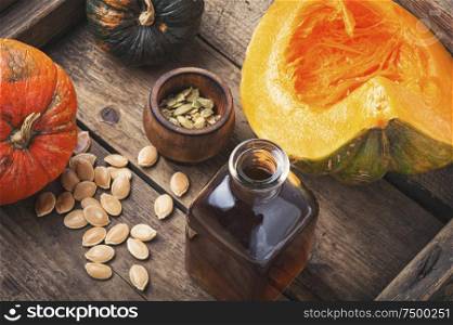 Pumpkin and pumpkin seed oil on wooden table. Bottle of pumpkin oil