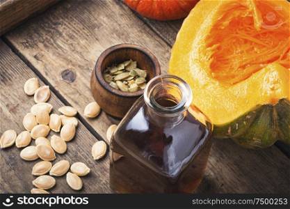 Pumpkin and pumpkin seed oil on wooden table. Bottle of pumpkin oil