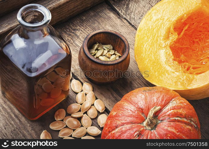 Pumpkin and pumpkin seed oil on wooden table. Bottle of pumpkin oil