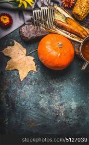 Pumpkin autumn cooking. Hokkaido pumpkin on kitchen table background with vegetables, fork and fall leaves, top view