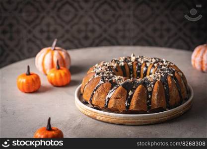 Pumpkin bundt cake with chocolate glaze and nuts on top, top view. Pumpkin bundt cake