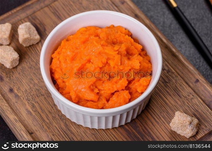 Pumpkin carrot baby puree in bowl on a dark background, top view. Fresh orange squash vegetable pumpkin carrot puree. Pumpkin carrot baby puree in bowl on a dark background