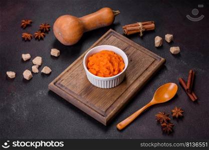 Pumpkin carrot baby puree in bowl on a dark background, top view. Fresh orange squash vegetable pumpkin carrot puree. Pumpkin carrot baby puree in bowl on a dark background