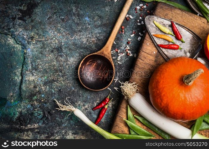 Pumpkin cooking on rustic kitchen table background with ingredients and wooden cooking spoon, top view, place for text