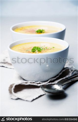Pumpkin cream soup in bowl over grey concrete background, copy space, vertical composition