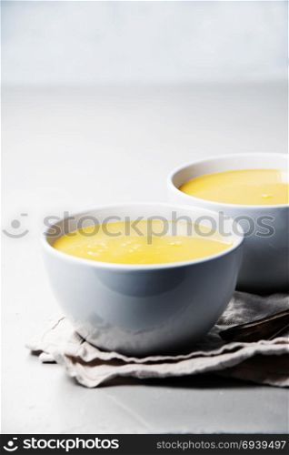Pumpkin cream soup in bowl over grey concrete background, copy space, vertical composition