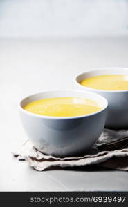 Pumpkin cream soup in bowl over grey concrete background, copy space, vertical composition