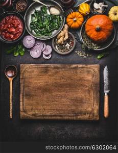 Pumpkin dish cooking. Food background with wooden cutting board, kitchen knife and spoon. Various vegetarian seasonal ingredients for tasty winter or autumn meal, top view. Clean healthy eating
