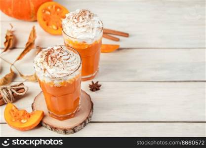 Pumpkin latte with whipped cream on a light wooden background. Hot spicy smoothie. Vegetable vegan drink. Copy space.. Pumpkin latte with whipped cream on light wooden background. Hot spicy smoothie. Vegetable vegan drink. 