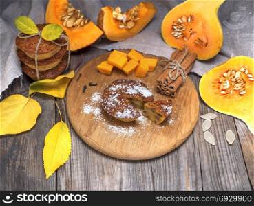 pumpkin muffins and fresh pumpkin slices on a black wooden background, top view