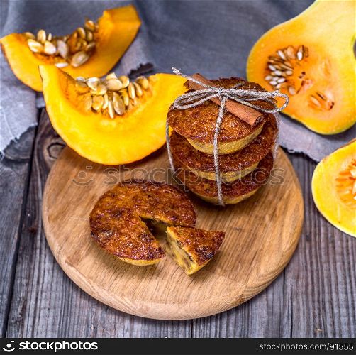 pumpkin muffins on a wooden board and fresh pieces of pumpkin, top view