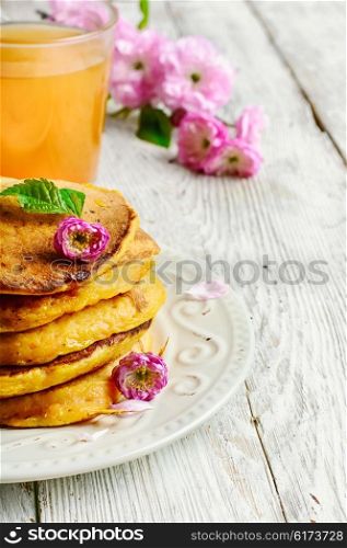 pumpkin pancakes with light dishes and glass of juice. pancakes with pumpkin