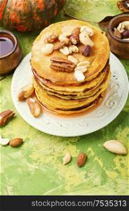 Pumpkin pancakes with maple syrup and mix of nuts. Pancakes with maple syrup.