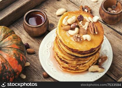 Pumpkin pancakes with maple syrup and nuts. Delicious pancakes on wooden table