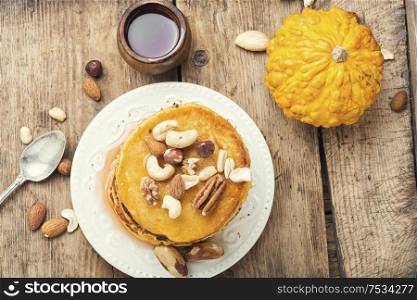 Pumpkin pancakes with maple syrup and nuts. Delicious pancakes on wooden table