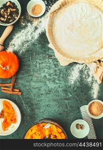 Pumpkin pie cooking : dough in backing form, filling and ingredients on dark rustic background, top view , retro styled