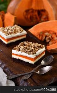 Pumpkin pie - light, creamy dessert with cheese cream and pumpkin layers topped with chopped nuts
