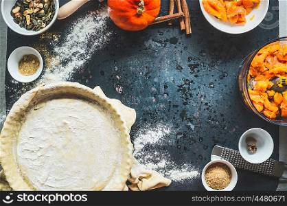 Pumpkin pie preparation on dark rustic background, top view, frame