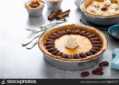 Pumpkin pie with cinnamon, pecan nuts and whipped cream for Thanksgiving.