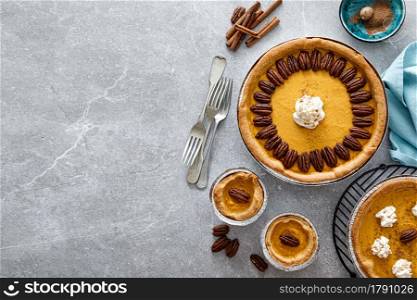 Pumpkin pie with cinnamon, pecan nuts and whipped cream for Thanksgiving, top view.