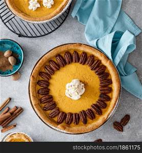 Pumpkin pie with cinnamon, pecan nuts and whipped cream for Thanksgiving, top view.