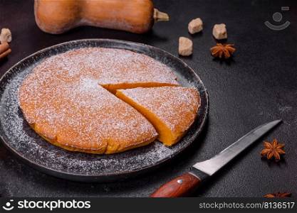 Pumpkin pie with whipped cream and cinnamon on a dark background, top view. Pumpkin pie, tart made for Thanksgiving day with whipped cream on a black plate