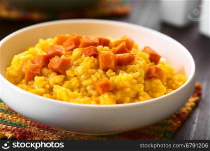 Pumpkin risotto prepared with pumpkin puree, roasted pumpkin pieces on top, photographed with natural light (Selective Focus, Focus in the middle of the image)