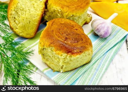 Pumpkin Scones with garlic and dill on a green napkin, yellow pumpkin slices on the background light wooden boards