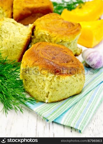 Pumpkin Scones with garlic and dill on a kitchen towel, yellow pumpkin slices on the background of wooden boards