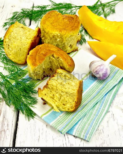 Pumpkin Scones with garlic and dill on a napkin, yellow pumpkin slices on the background light wooden boards