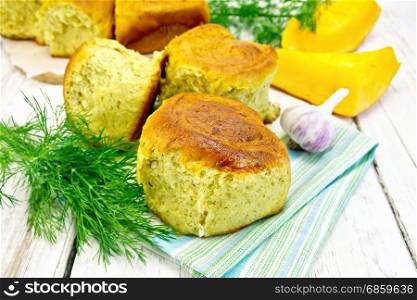 Pumpkin Scones with garlic and dill on a napkin, yellow pumpkin slices on the background of wooden boards