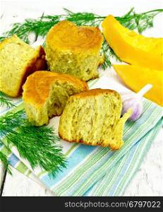 Pumpkin Scones with garlic and dill on a towel, yellow pumpkin slices on the background light wooden boards