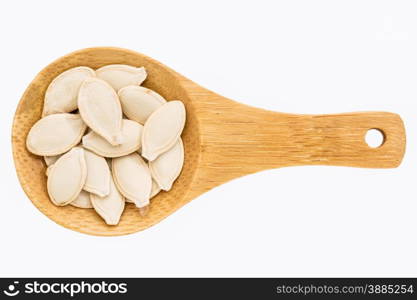 pumpkin seeds on a small wooden spoon isolated on white with a clipping path
