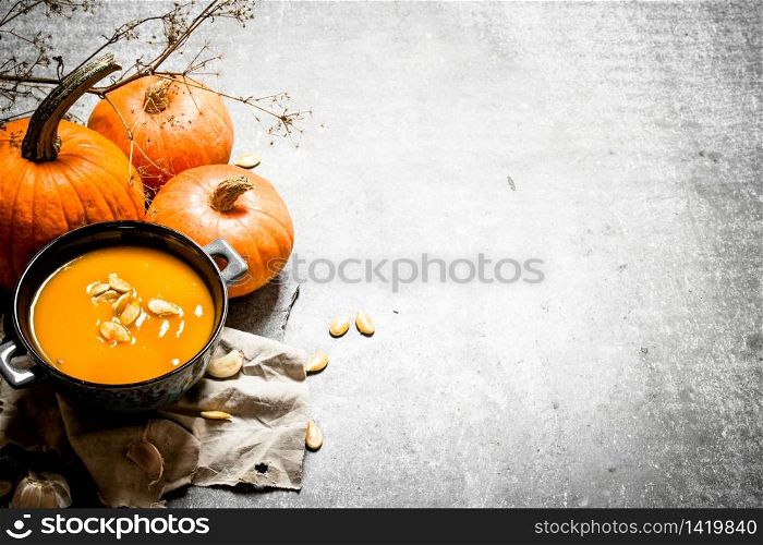 Pumpkin soup from a ripe pumpkin with seeds. On the stone table.. Pumpkin soup