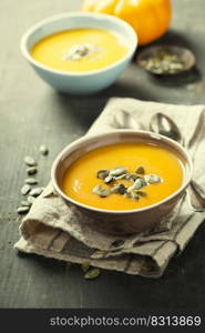 Pumpkin soup in a bowl on a wooden surface selective focus. Pumpkin soup in a bowl on a wooden surface with copy space