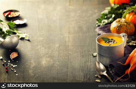 Pumpkin soup in a metal pot on a wooden surface