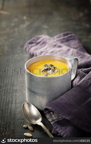 Pumpkin soup in a metal pot on a wooden surface